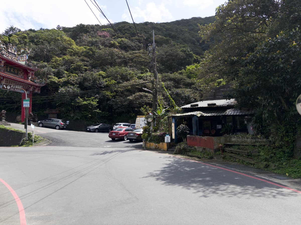 金光路山路旁的食不厭老屋，鐵皮屋頂垂著藤蔓、靠在山壁邊