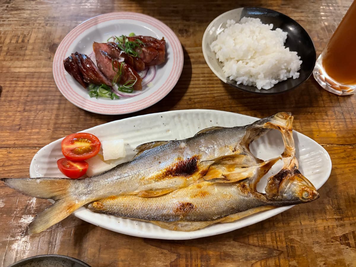 食不厭招牌的午仔魚一夜干,剖開後皮面煎得金黃,旁邊配小番茄與醃蘿蔔