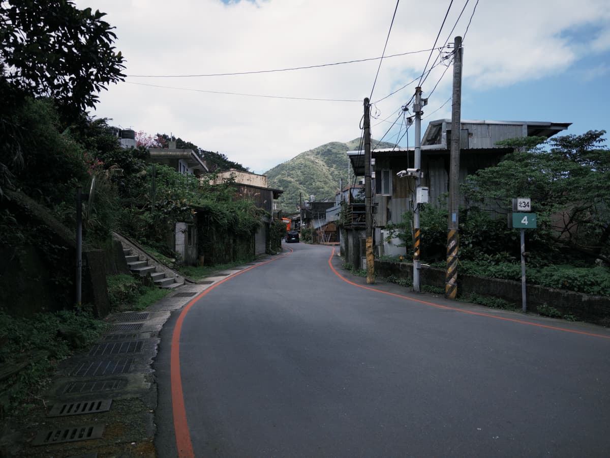 金瓜石金光路的山城街景,道路兩旁是山坡老屋與遠山