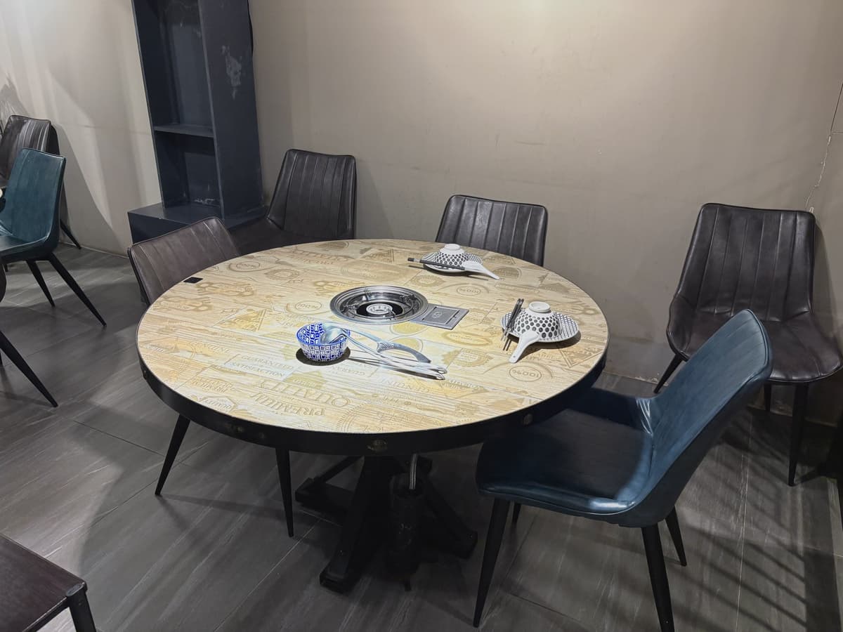 圓桌座位配四張皮椅,桌面已擺好餐具與爐口